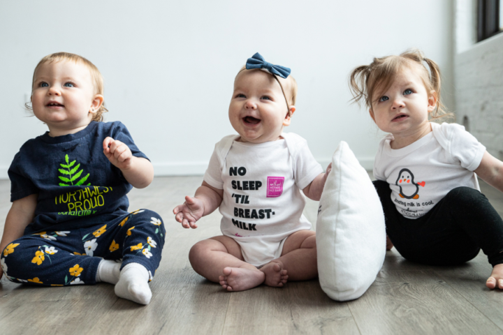 Three babies sitting on the floor and smiling