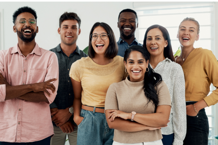 A group of seven people standing together and happily posing for the camera